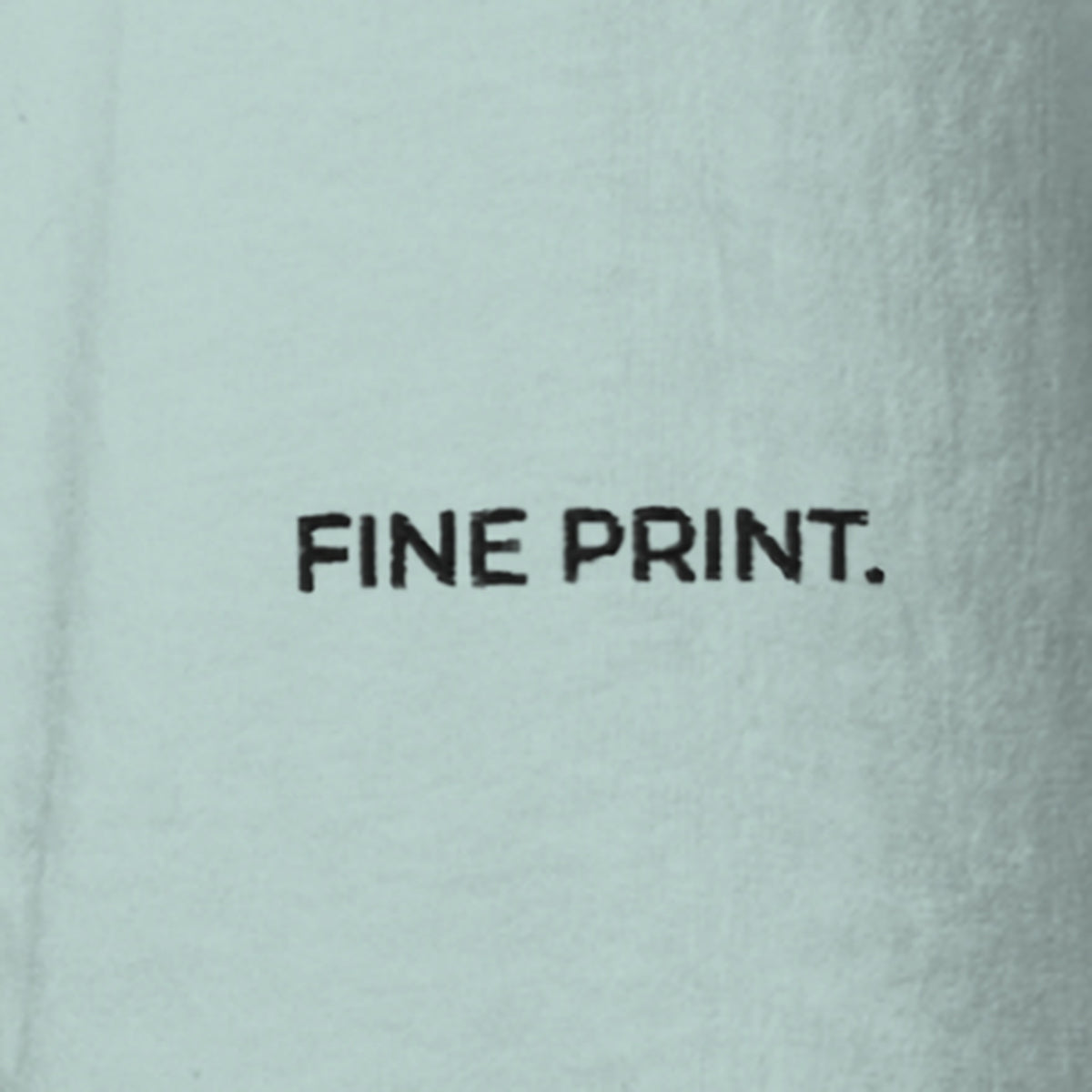 Close-up of the left sleeve of the Fine Print Tee: FINE PRINT. embroidered in small black capitals on Agave cotton.