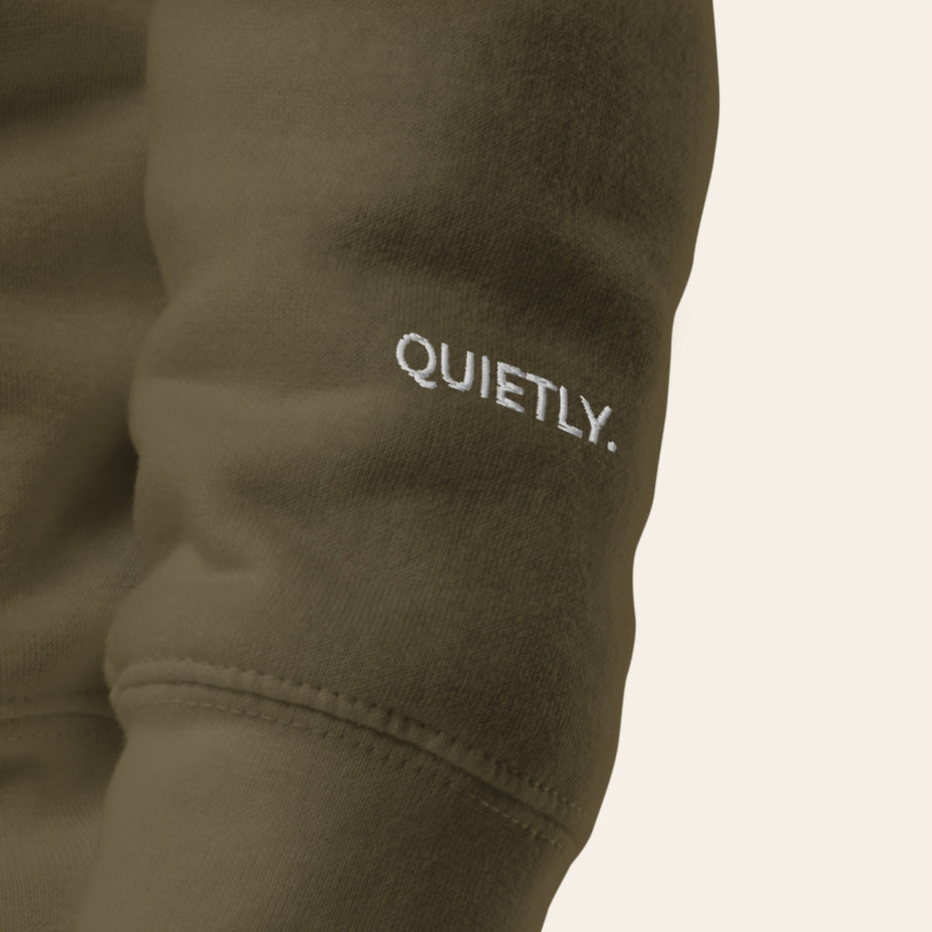 Close-up of the left cuff of the Second Look Hoodie, embroidered QUIETLY. in white thread.