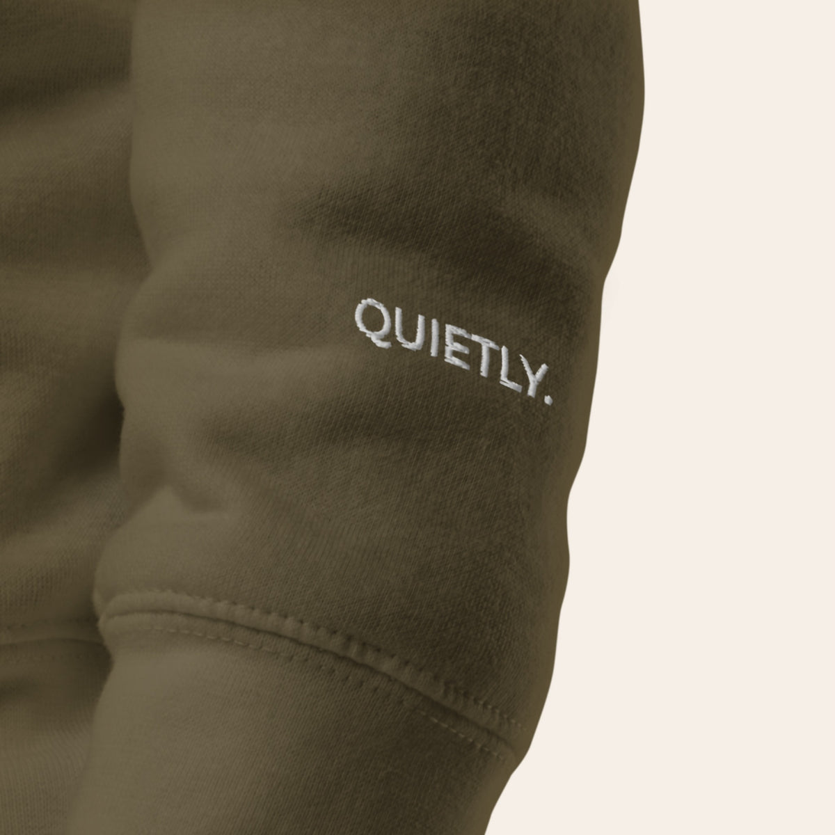 Close-up of the left cuff of the Second Look Hoodie, embroidered QUIETLY. in white thread.