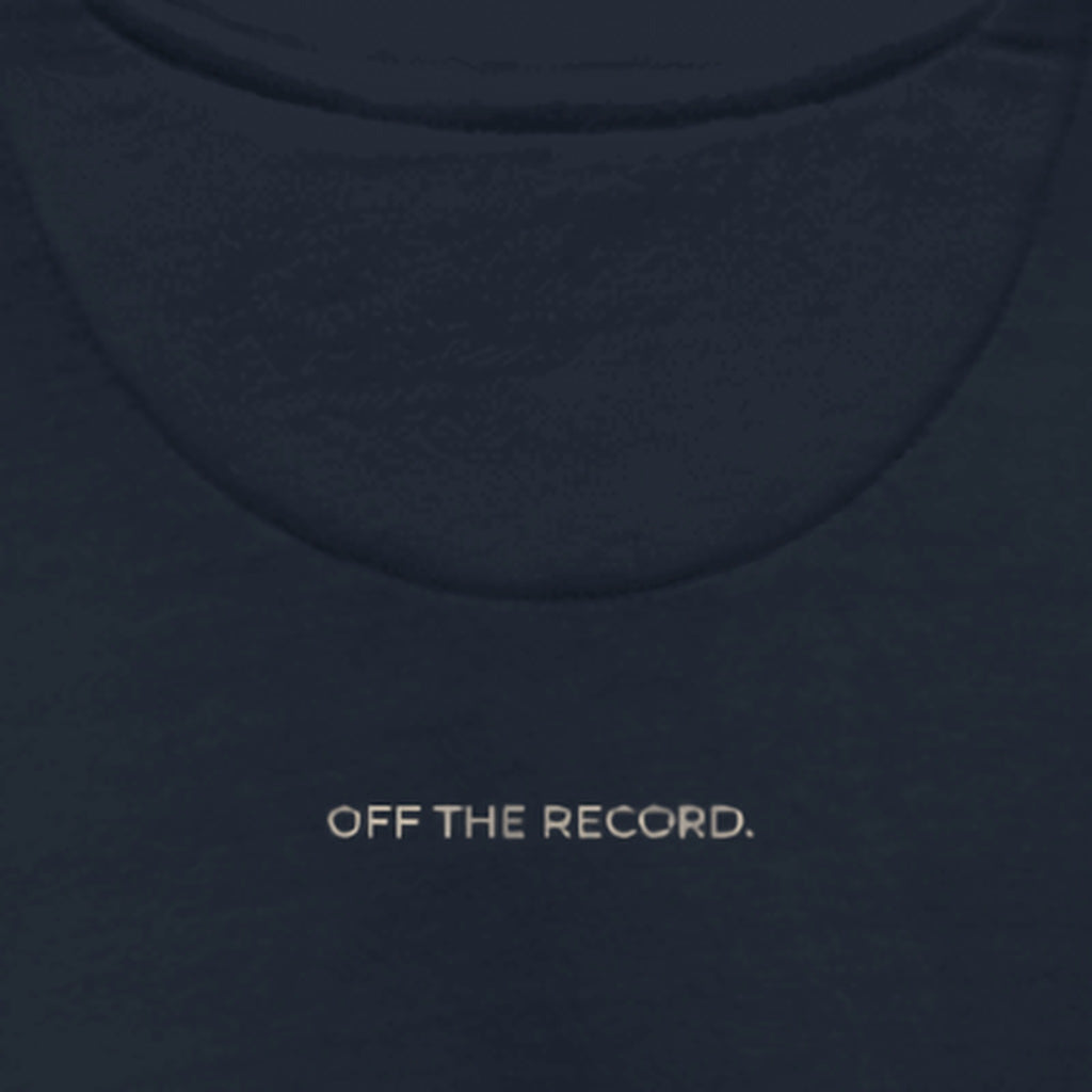 Close-up of the upper back of the Off The Record Crew, just below the collar: OFF THE RECORD. printed in sand on navy fleece.