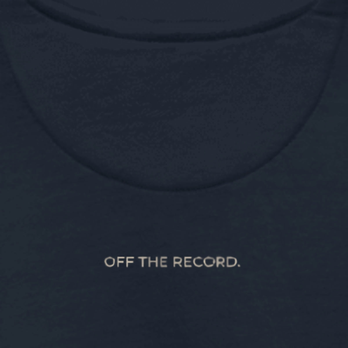 Close-up of the upper back of the Off The Record Crew, just below the collar: OFF THE RECORD. printed in sand on navy fleece.
