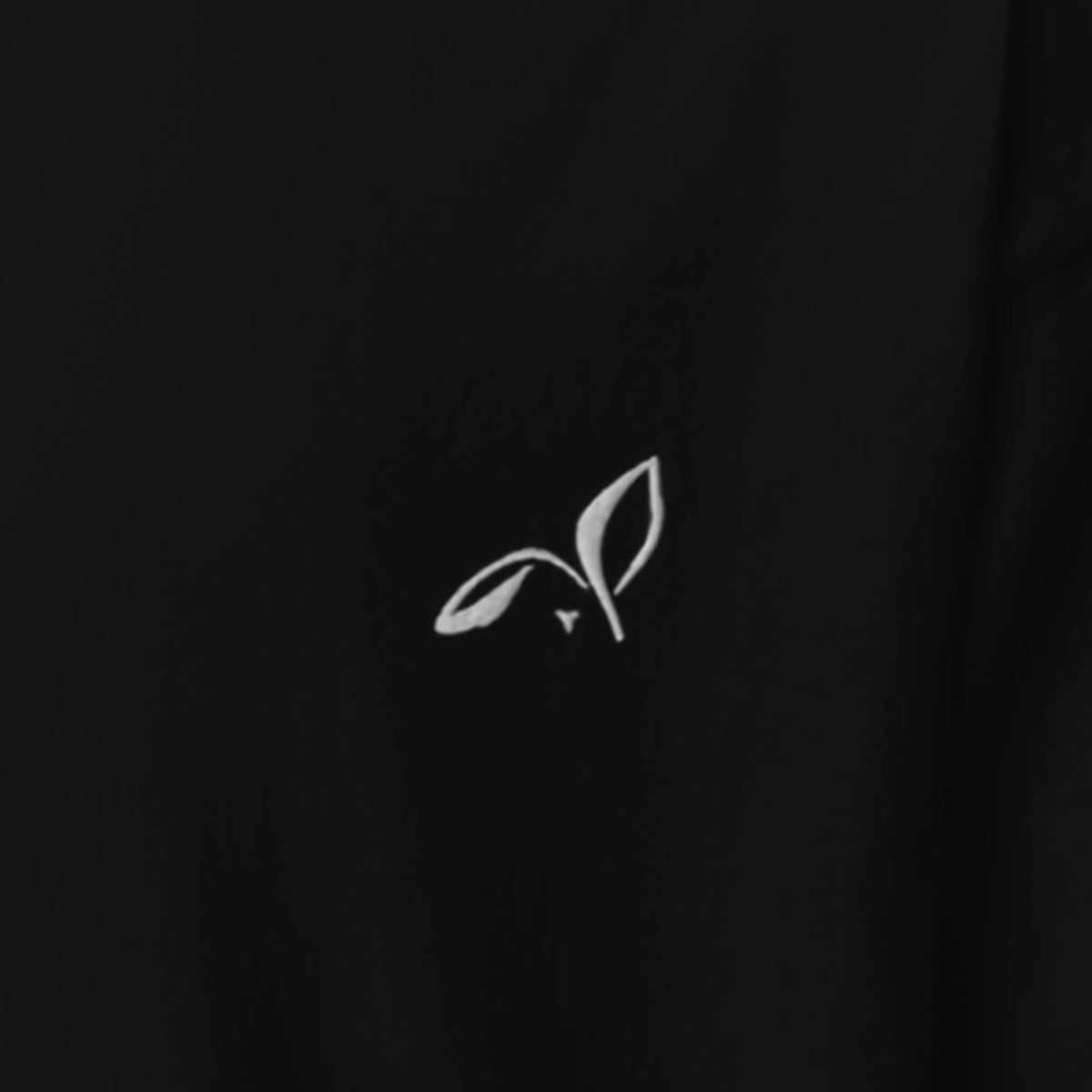 Close-up of the white embroidered LOUPI GANG rabbit on the left chest of the Black Signature Embroidered Tee.