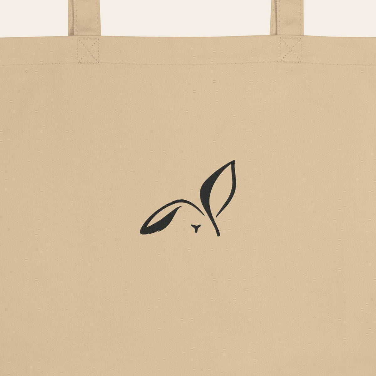 LOUPI GANG Everyday Organic Tote in Oyster, close-up of the black embroidered rabbit and handle stitching